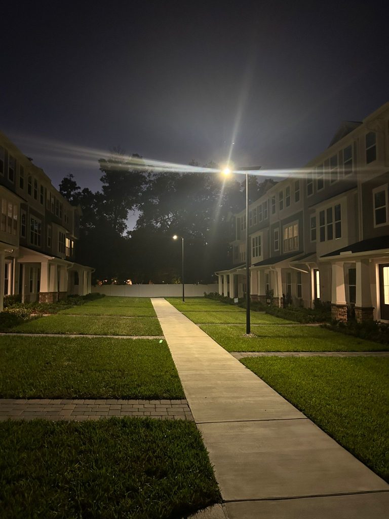 SolarPath solar street light illuminating a walkway between townhomes at night